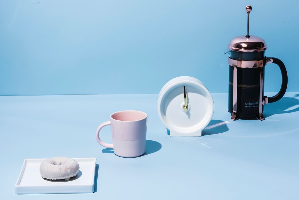 a cup of coffee, a donut, and a coffee maker on a blue