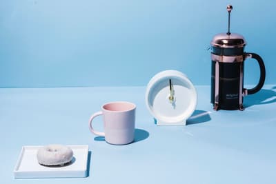 a cup of coffee, a donut, and a coffee maker on a blue