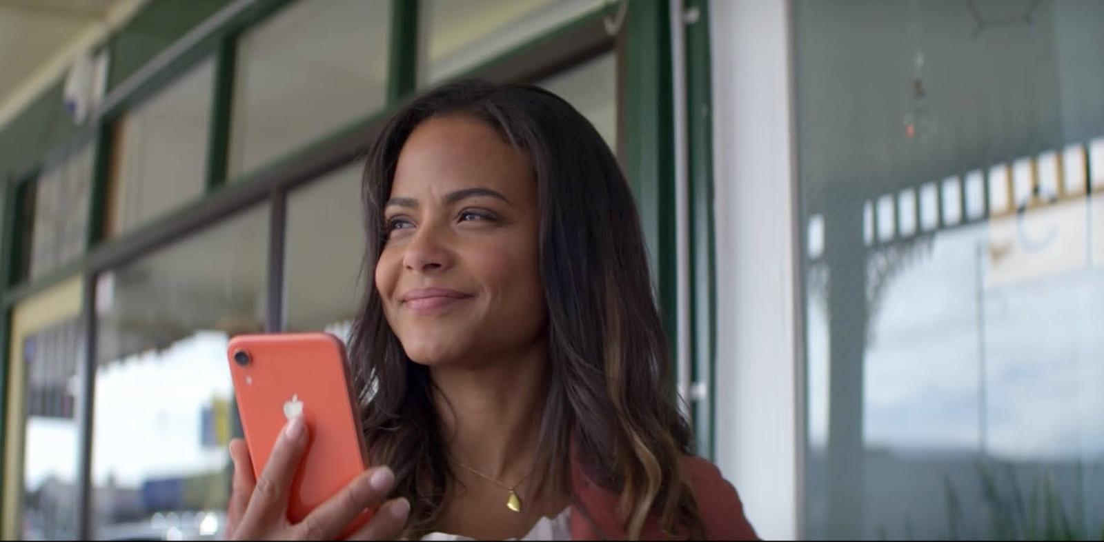 a woman holding a red cell phone in front of a window