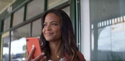 a woman holding a red cell phone in front of a window