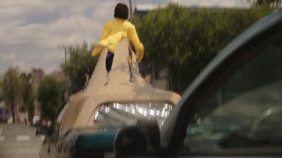 a man in a yellow shirt jumping off a car