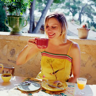 a woman sitting at a table with a cup of coffee