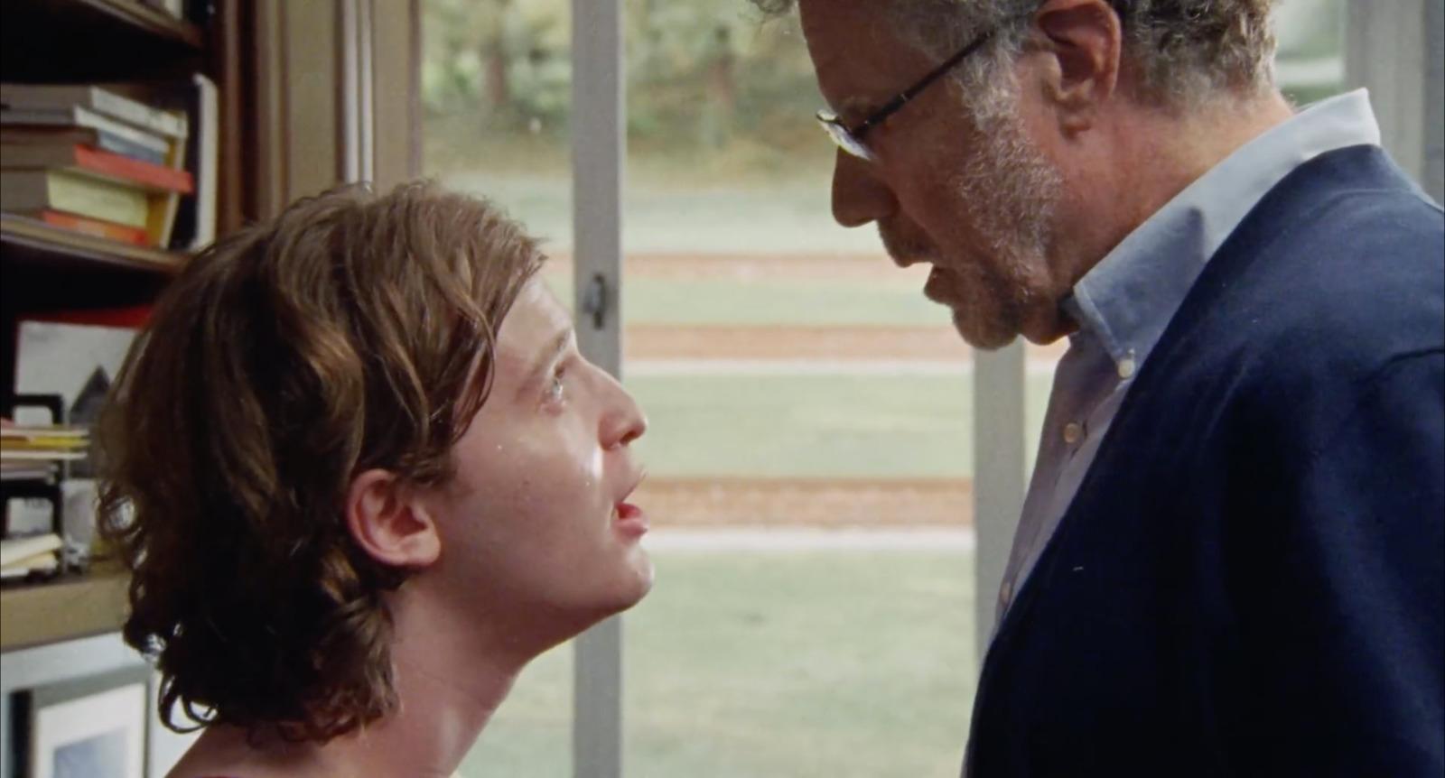 a man standing next to a woman in front of a window