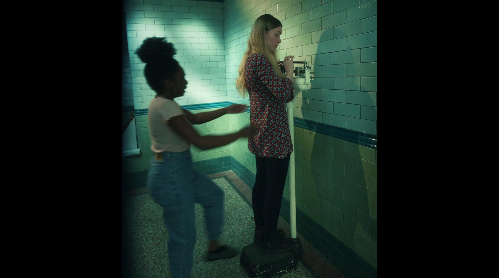 two women are standing in a public restroom