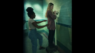 two women are standing in a public restroom