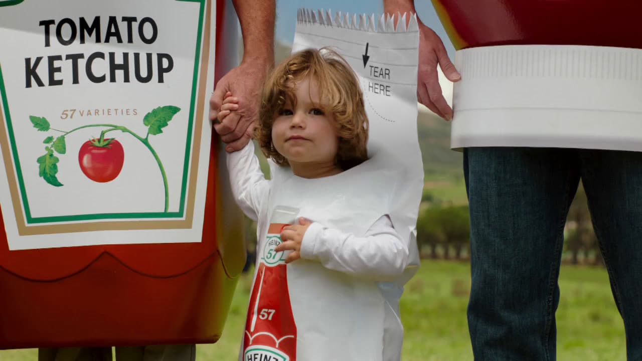a little girl standing next to a giant ketchup bottle