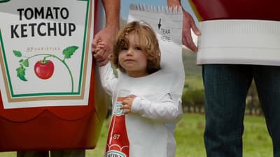 a little girl standing next to a giant ketchup bottle
