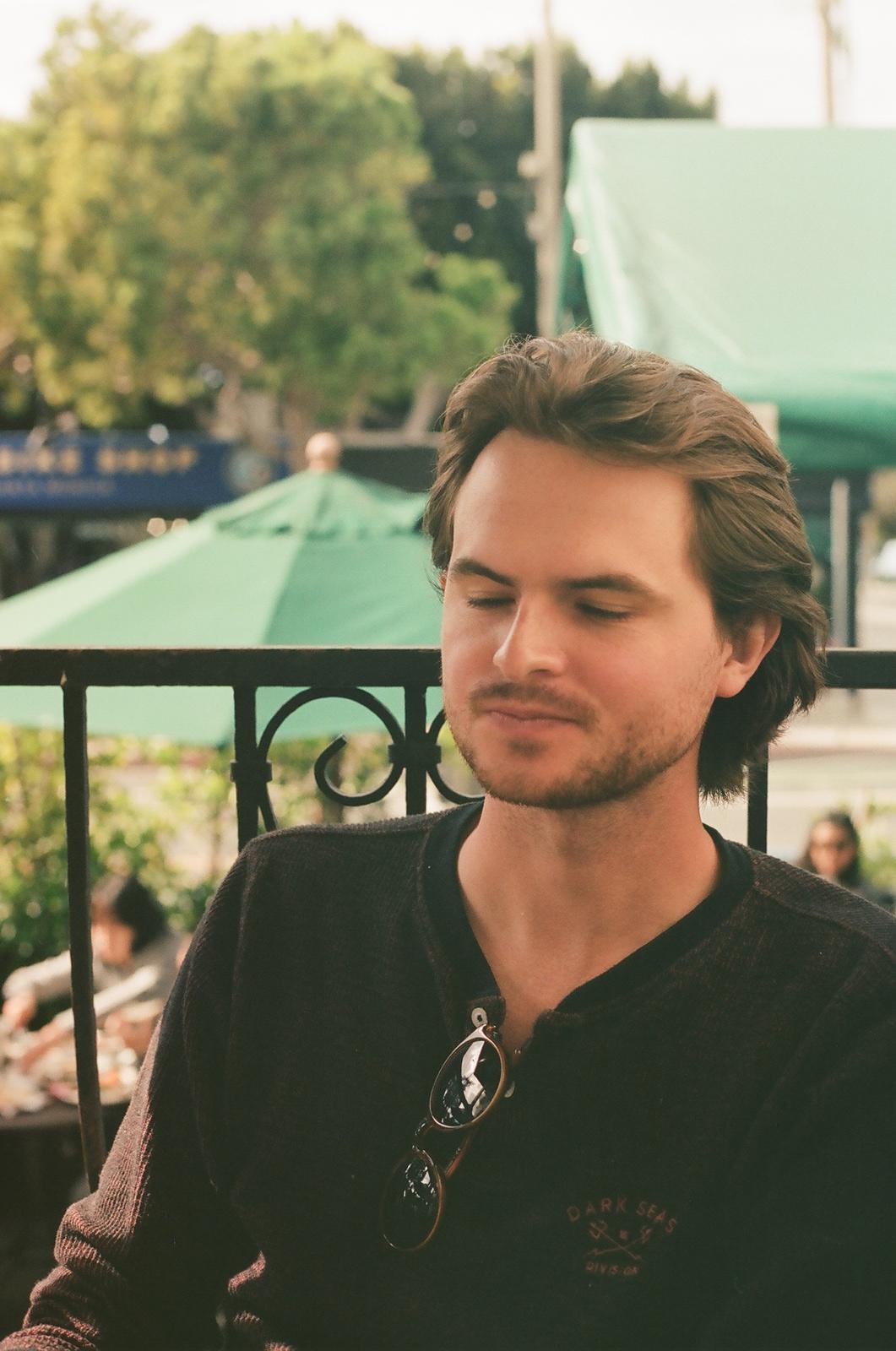 a man leaning against a fence with his eyes closed