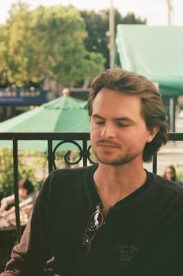 a man leaning against a fence with his eyes closed