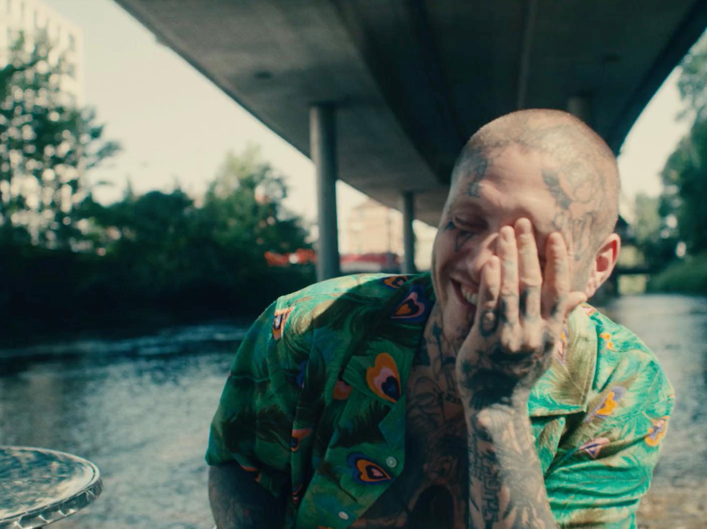 a man with tattoos on his face standing next to a river