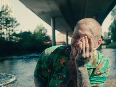 a man with tattoos on his face standing next to a river