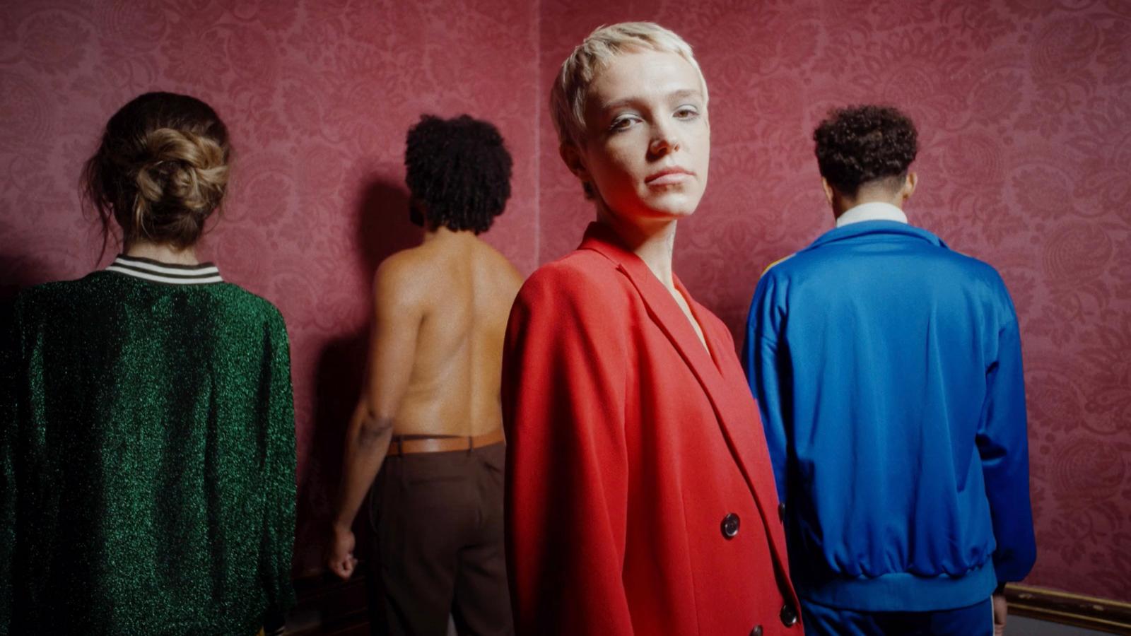 a group of people standing in front of a red wall