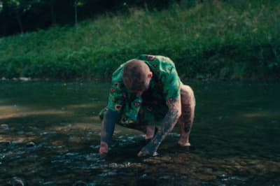 a man in a green shirt standing in a river