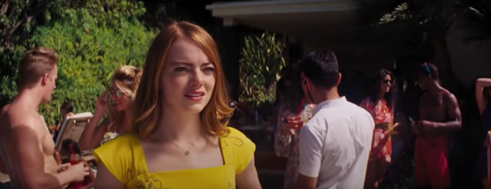 a woman in a yellow dress standing in front of a group of people