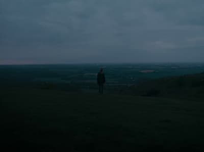 a person standing on top of a lush green hillside