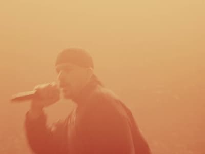 a man standing in the fog with a bottle in his hand