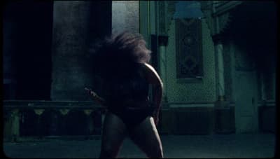a woman in a bodysuit walking in the dark