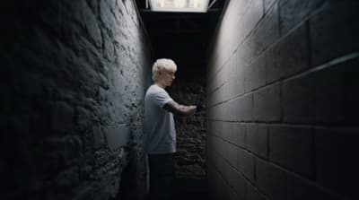 a man standing in a narrow alley between two walls