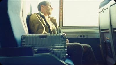 a man sitting on a train next to a window