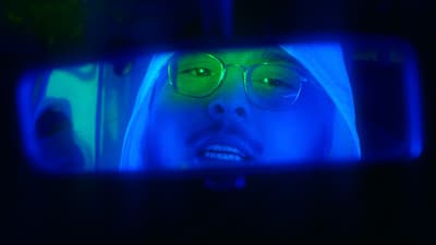 a man with glasses is looking at himself in the mirror