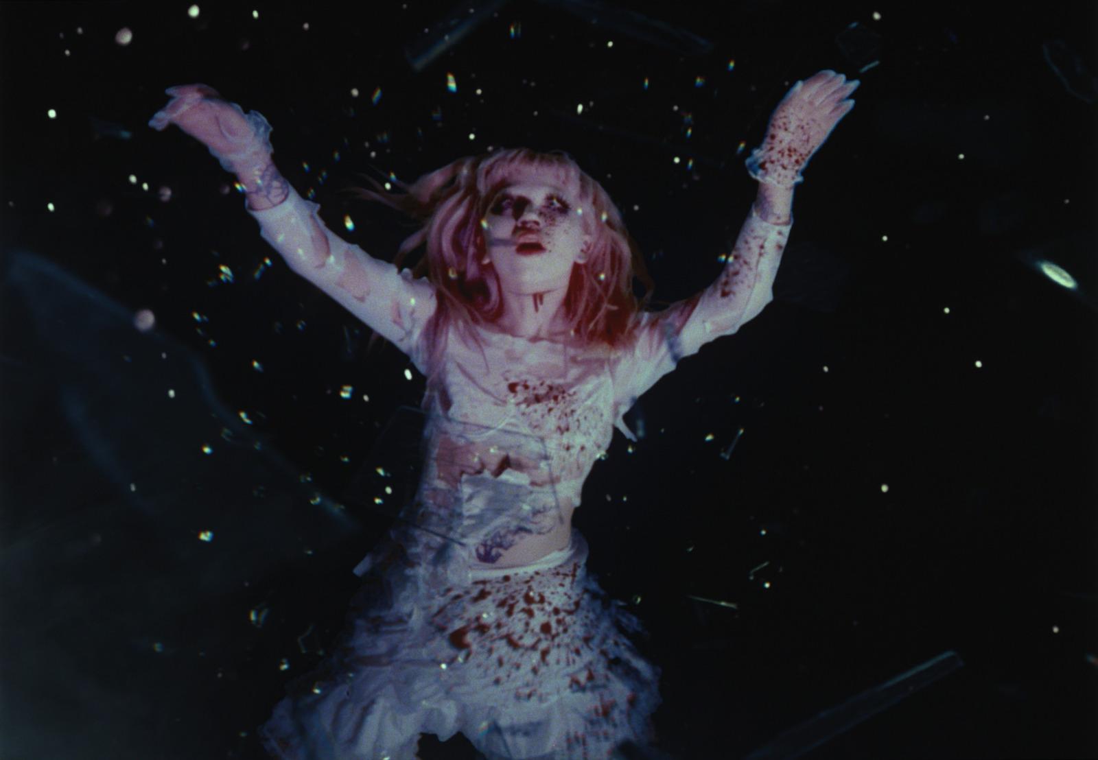 a woman in a white dress with her arms up in the air