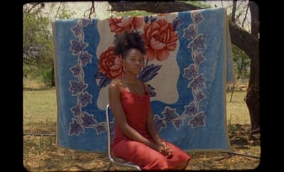 a woman sitting on a chair in front of a quilt