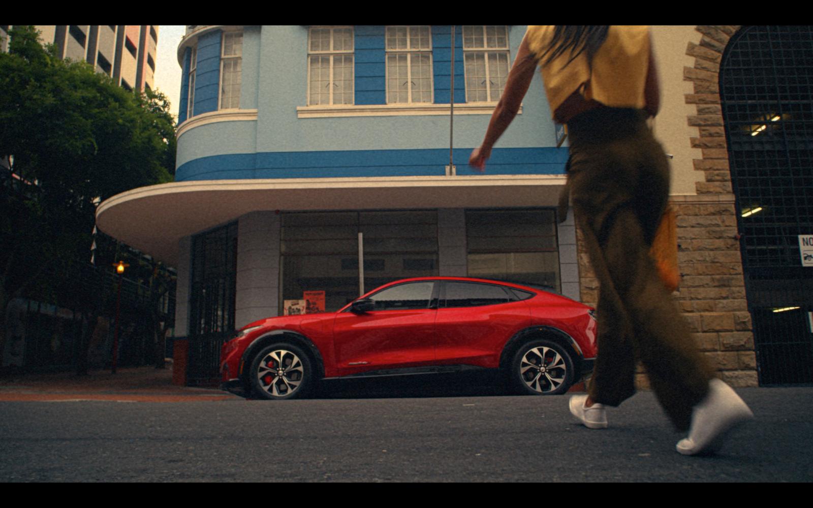 a person walking past a red car on a city street