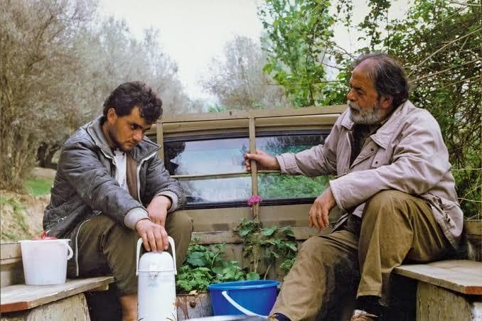 a couple of men sitting on top of a wooden bench
