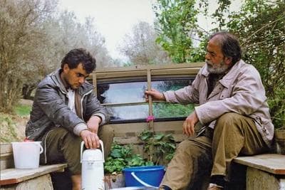 a couple of men sitting on top of a wooden bench