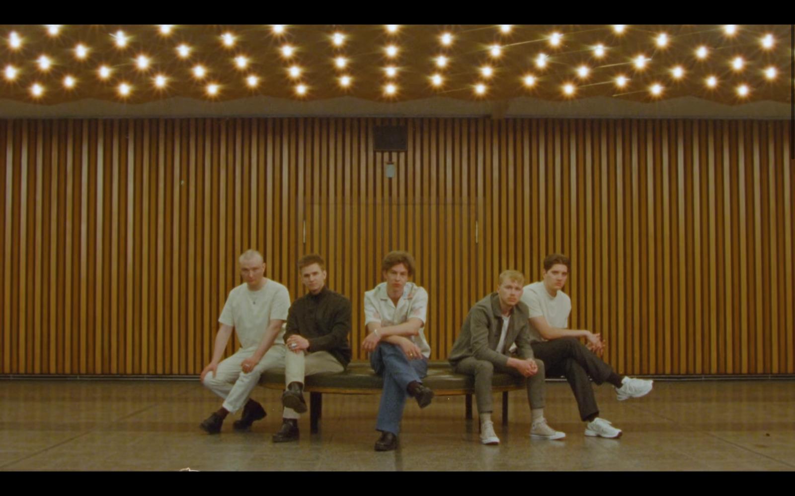 a group of young men sitting on top of a wooden bench