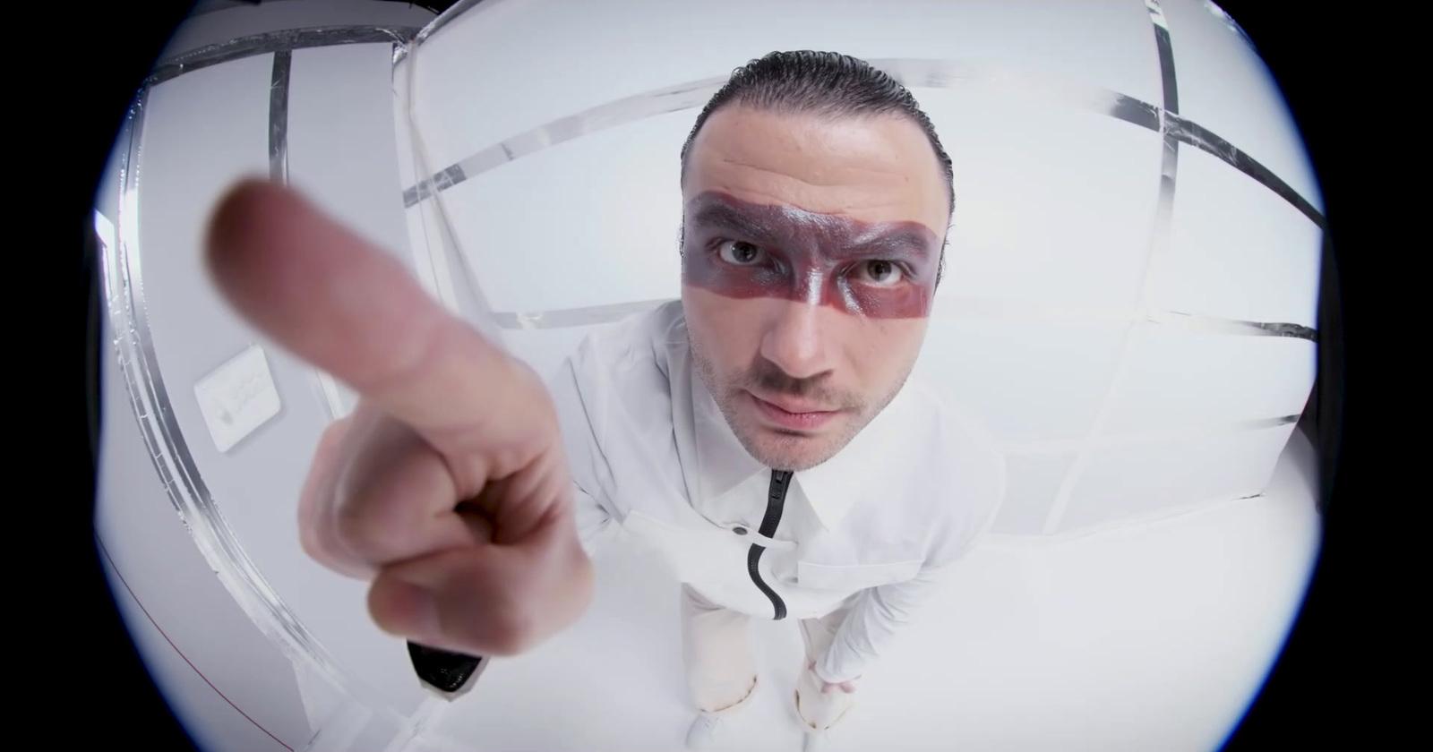 a man in a white shirt pointing a finger at the camera