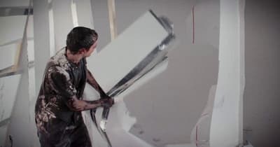 a man holding a large pair of scissors in a room