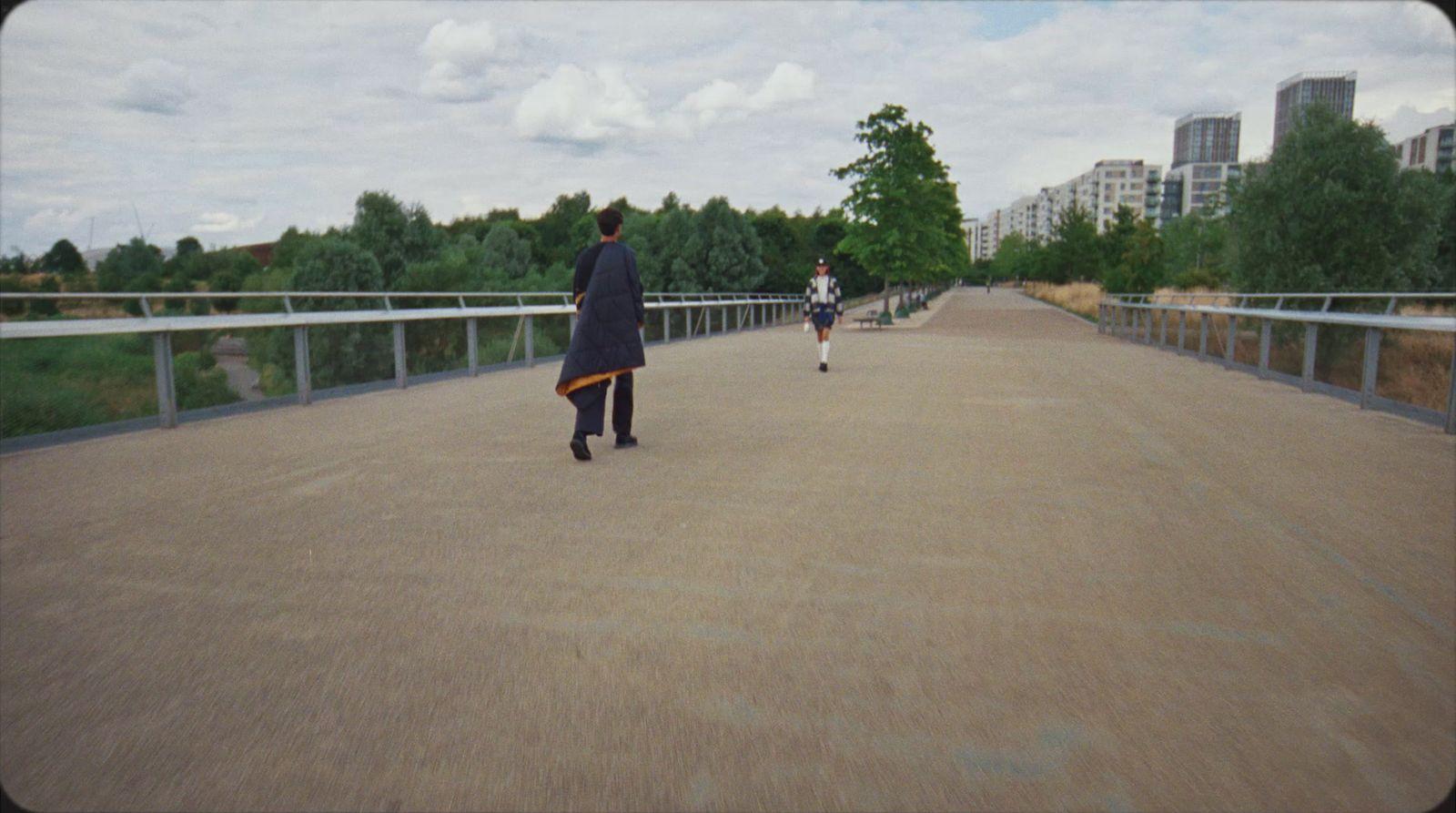 two people walking across a bridge in a city