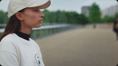a woman wearing a baseball cap and a white jacket