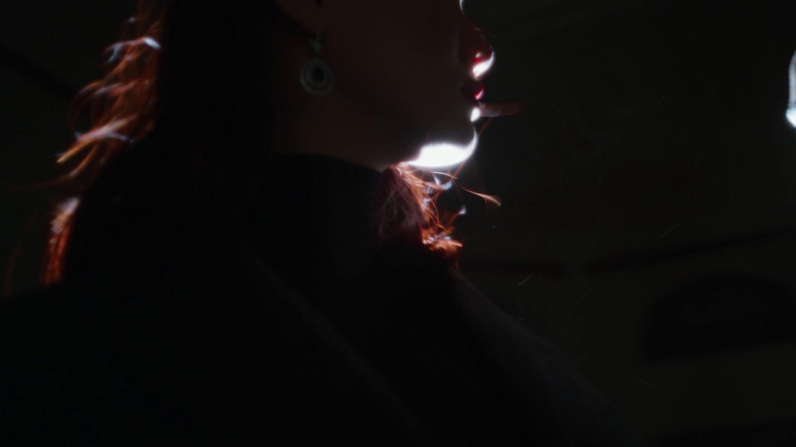 a woman in a dark room with a light shining on her face