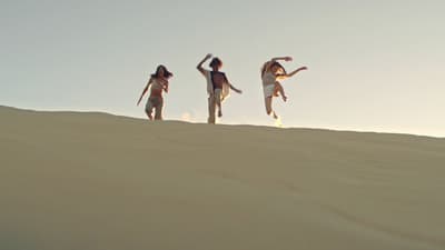 a group of people standing on top of a sandy hill