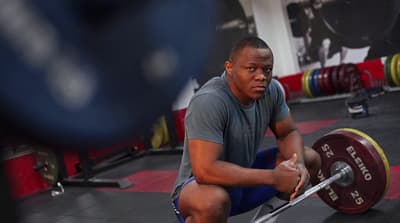 a man squatting down with a barbell in his hand