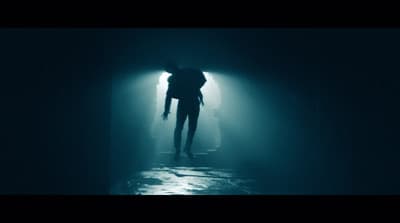 a person standing in a dark tunnel holding an umbrella