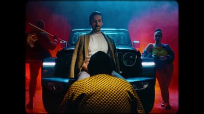 a man standing in front of a car with other people around him