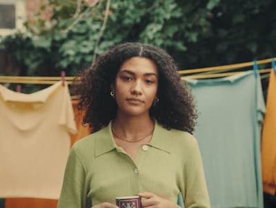 a woman holding a cup of coffee in front of clothes