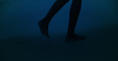 a woman standing in the dark with her legs crossed