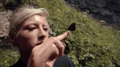a woman pointing a finger at a butterfly