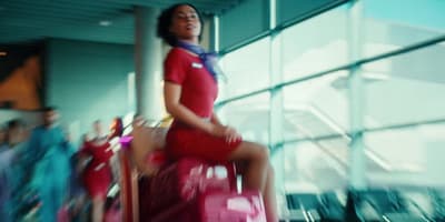 a woman sitting on top of a red suitcase