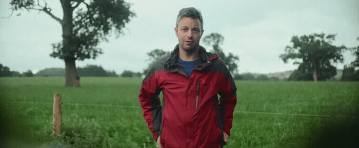 a man in a red jacket standing in a field