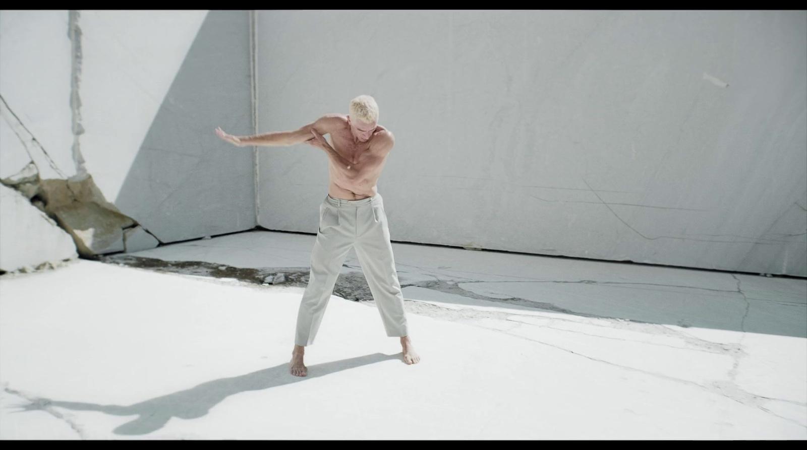 a man with no shirt on standing in the snow