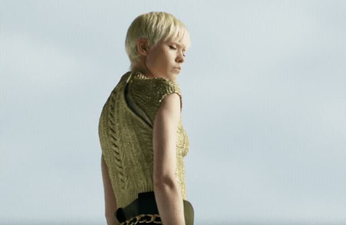 a woman with blonde hair wearing a green sweater