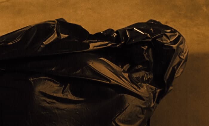 a pile of black plastic bags sitting on top of a floor