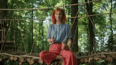 a woman sitting on a rope bridge in the woods