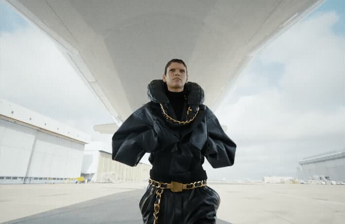 a man in a black outfit with a chain around his neck