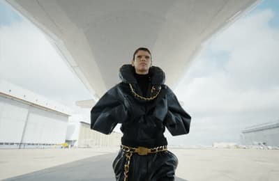 a man in a black outfit with a chain around his neck